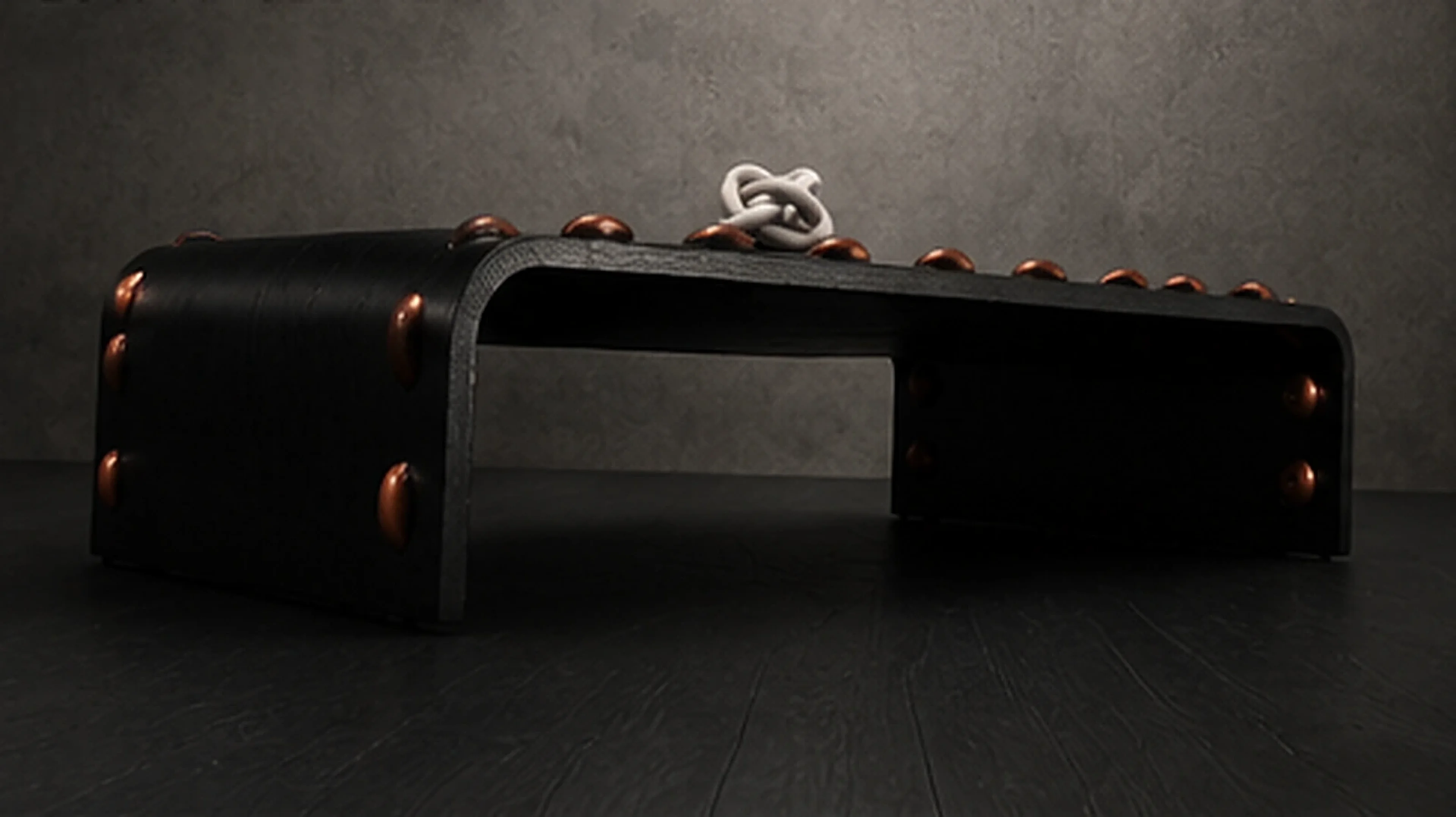 The Leather Stud Coffee Table, a low dramatic angle showing the black leather waterfall form and thread studs